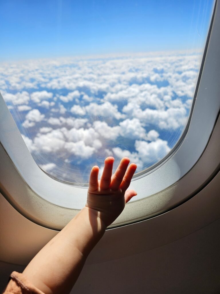 Langstreckenflug mit Baby – Babyhand am Flugzeugfenster